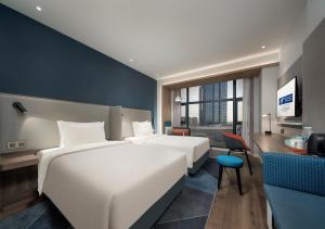 a hotel room with two beds and a desk at Holiday Inn Express Shanghai Qingpu New City, an IHG Hotel in Shanghai