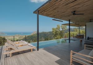 a villa with a swimming pool and a wooden deck at DUNIA LOMBOK - Villas with Ocean View in Selong Belanak