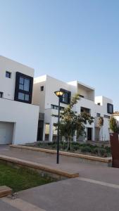 uma luz de rua em frente a um edifício branco em Taghazout bay - Tawenza Medina - Apt avec piscine partagée et Jardin em Tamraght Ouzdar