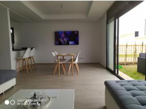 uma sala de estar com uma mesa e uma televisão na parede em Taghazout bay - Tawenza Medina - Apt avec piscine partagée et Jardin em Tamraght Ouzdar