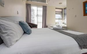 Seaview and Spa at Torbay في ألباني: غرفة نوم بسرير كبير مع شراشف بيضاء ومخدات زرقاء