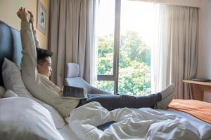 a person laying on a bed with a laptop at Holiday Inn Express Kota Kinabalu City Centre, an IHG Hotel in Kota Kinabalu