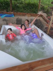 Tre ragazze sono sedute in una vasca idromassaggio. di Hospedaje Rural El Rancho de Amelia y Juancho a Silvania