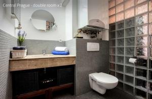 a bathroom with a sink and a toilet and a mirror at Kent Ridge Loft in Prague