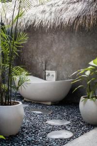 烏魯瓦圖的住宿－Villa Amantes Bingin，带浴缸和盆栽植物的浴室
