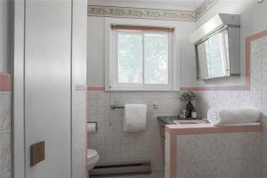 a bathroom with a toilet and a sink and a window at Gorgeous Lakefront 5-Bedroom Cottage 40min to TOR. in Manvers