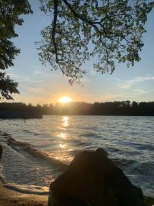 a sunset over a body of water with a rock at Uroczy Domek in Złocieniec +19 photos