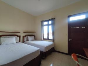 a hotel room with two beds and a window at Adi Pelita Sari Bali in Denpasar