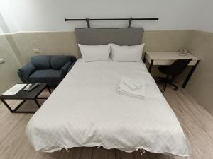 1 dormitorio con 1 cama blanca grande y 1 sofá azul en No 9 Hotel-九號文旅, en Tainan