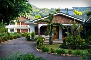 a house with a palm tree in front of it at Villa de Roses in Beau Vallon