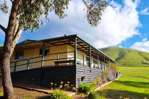 a house in a field with a hill in the background at The Village Green Bunkhouse in Strath Creek