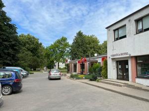 a street with cars parked in front of a building at Hotel DANIELA in Nīca