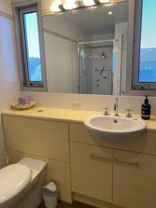 a bathroom with a sink and a toilet and a mirror at Bayview Retreat - Esplanade home w wifi in Wallaroo