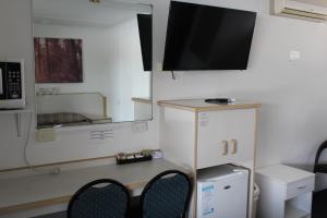 Habitación pequeña con escritorio y TV en la pared. en Tally Ho Motor Inn, en Tenterfield
