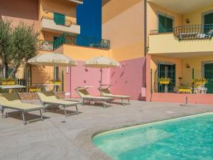 una piscina di fronte a un edificio con sedie e ombrelloni di Belvilla by OYO Mirti Bianchi Bilo a Santa Teresa di Gallura