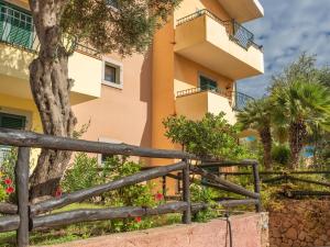 un edificio con una valla y un árbol delante de él en Belvilla by OYO Mirti Bianchi Bilo, en Santa Teresa Gallura