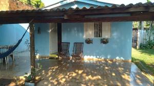 a patio with chairs and a blue house at Casa Pedacinho do Céu in Nobres