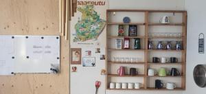 Il comprend une cuisine équipée d'un réfrigérateur et d'une étagère avec des tasses. dans l'établissement Simple private bedroom in a former Finnish School at the countryside, à Hyrsylä