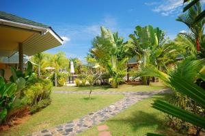 a garden with palm trees and a house at Palm Garden Resort in Khao Lak