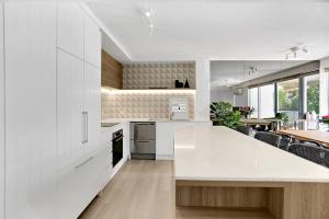 a white kitchen with a large white counter top at The Cove Noosa - Apartment 22 in Noosa Heads