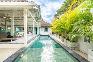 una piscina a sfioro nel cortile di una casa con palme di Plum Villa by Hombali a Canggu