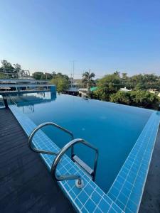 a blue swimming pool with a chair on the edge at Christella Hotel Laemchabang in Si Racha