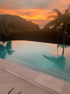 a swimming pool with a sunset in the background at The Cape at Wategos Pool Pavilion in Byron Bay
