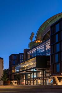 a large glass building with a curved roof at dusk at Oval Hotel at Adelaide Oval in Adelaide