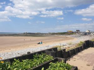 a beach with people sitting on the sand at 77 The Brambles in Porthcawl