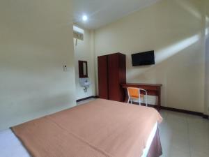 a bedroom with a bed and a desk and a tv at Adi Pelita Sari Bali in Denpasar