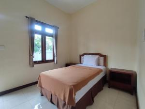 a bedroom with a bed and a window at Adi Pelita Sari Bali in Denpasar