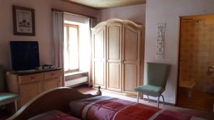 Garni Fluela Susch في سيور: غرفة نوم بسرير وكرسي ونافذة