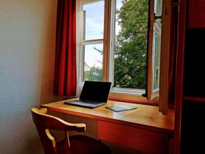 un ordinateur portable assis sur un bureau à côté d'une fenêtre dans l'établissement Sunrise Belvedere Pfronten, à Pfronten