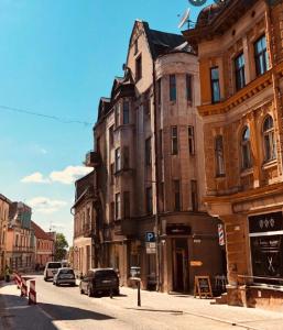 un antiguo edificio en una calle de la ciudad con coches aparcados en Boutique Hostel Cesis-X, en Cēsis