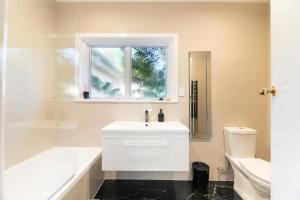 a white bathroom with a sink and a window at Grange Harbour View B&B in Tauranga +8 photos