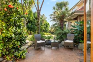 a patio with chairs and trees and a house at Grange Harbour View B&B in Tauranga