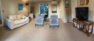 a living room with a couch and chairs and a tv at Grange Harbour View B&B in Tauranga