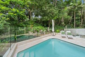 a swimming pool with two chairs and a fence at Little Cove Court - Apt 8 in Noosa Heads