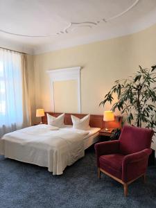 Hotel Vierseithof Luckenwalde في لوكنفالده: غرفة نوم بسرير ابيض وكرسي