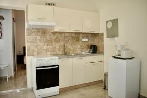 uma cozinha com armários brancos, um lavatório e um frigorífico em Astrinos Apartment, cosy and near to the beach! em Kato Daratso