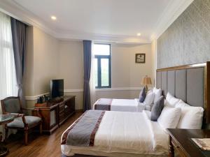 a hotel room with two beds and a television at AVS Hotel Phu Quoc in Phu Quoc