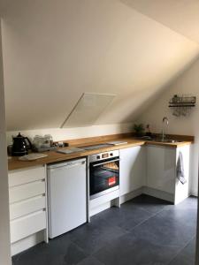 a kitchen with white cabinets and a stove top oven at Oakworth Lodge - New self contained studio in Heathfield