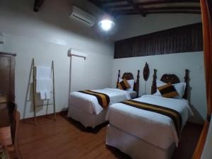 two beds in a room with white walls and wooden floors at Dem Ayem Heritage Guest House in Yogyakarta