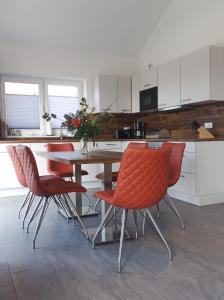 eine Küche mit einem Tisch und roten Stühlen in der Unterkunft Haus MoorRose in Schweiburg