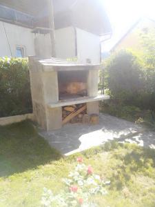 a stone outdoor oven in a yard with flowers at Manjina kuća in Fužine