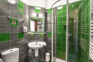uma casa de banho com azulejos verdes, um lavatório e um WC. em Apartamenty Rynek 20 em Pszczyna