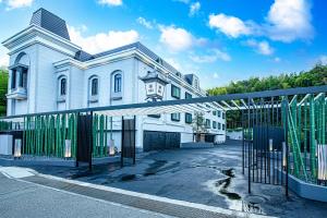 una casa blanca con una puerta delante de ella en ホテル継kei男塾ホテルグループ en Himeji