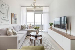 a white living room with a white couch and a tv at Frank Porter - Bloom Tower in Dubai
