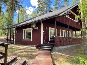 ein kleines rotes Haus mit einer Veranda und einer Terrasse in der Unterkunft Villa Huvikalliola, LaatuLomat in Sulkava