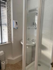 a white bathroom with a shower and a sink at The Elan Valley Hotel in Rhayader